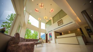 Un hall amplio con techo alto, ventanas grandes, mostrador de recepción y zona de estar con sofá y mesa.