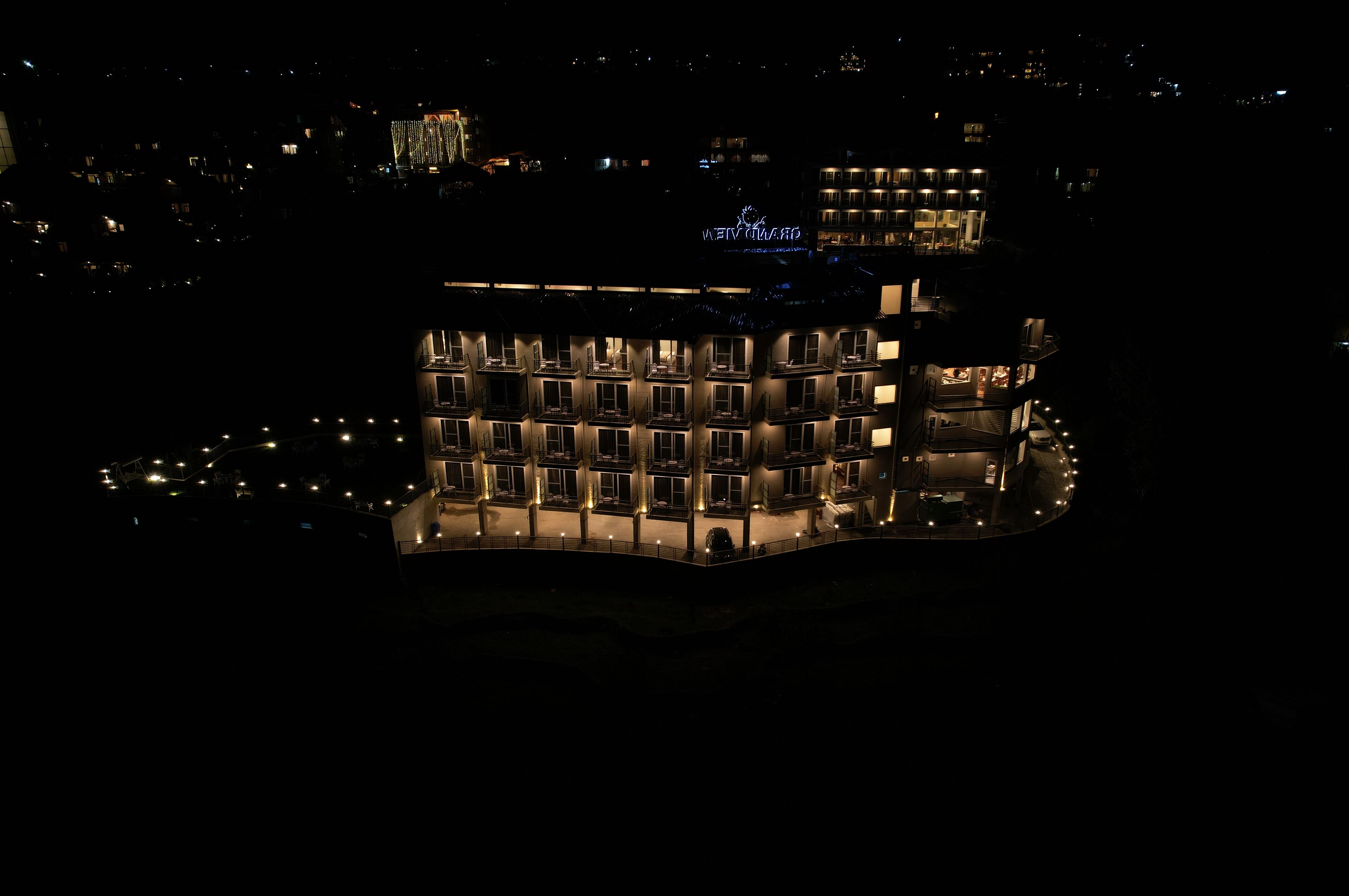Un hôtel à plusieurs étages doté d’une cour intérieure, de fenêtres illuminées et d’une enseigne bien visible.