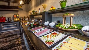 Buffet com diversos alimentos, incluindo carnes, queijos e vegetais.