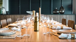 A dining table set with wine glasses and plates, a candle, and a decorative bottle in the center.