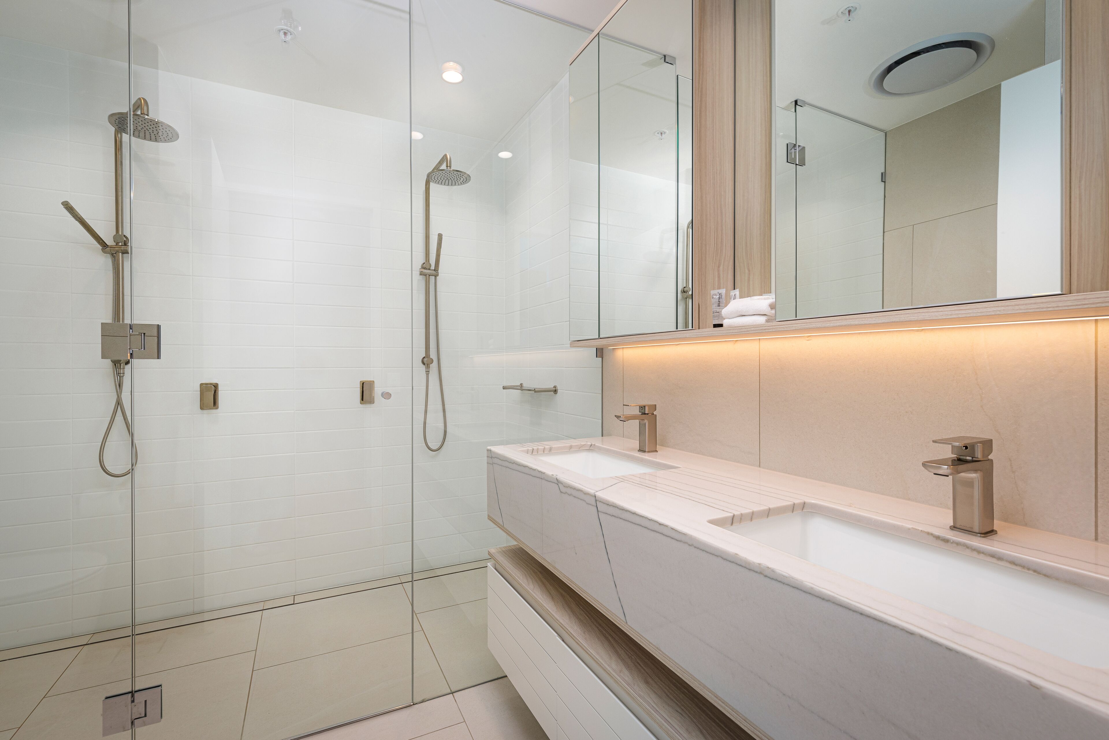 A modern bathroom with a glass-enclosed shower, a large mirror, and a white vanity with a sink.