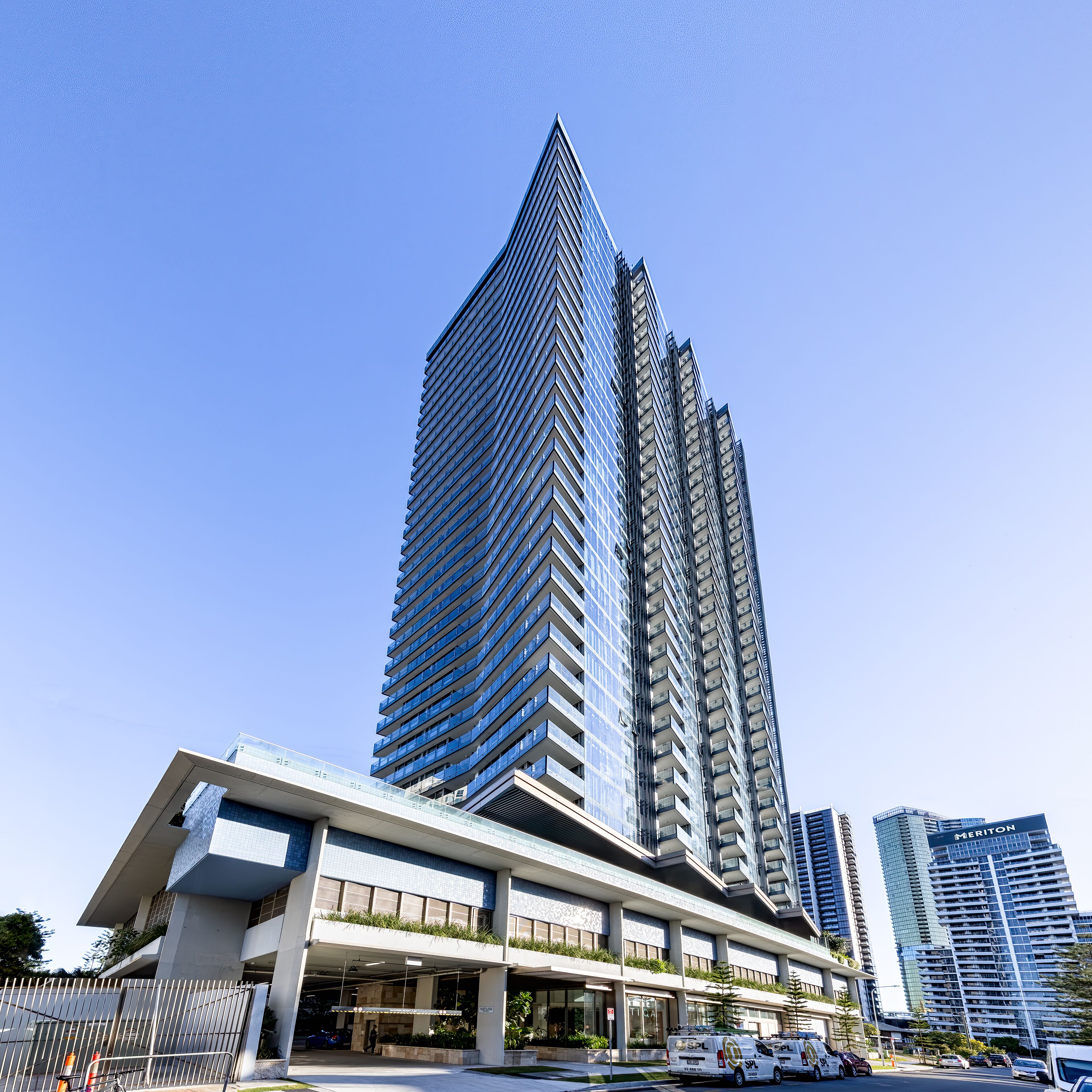 A modern high-rise building with a distinctive angular design, featuring multiple balconies and a glass facade.