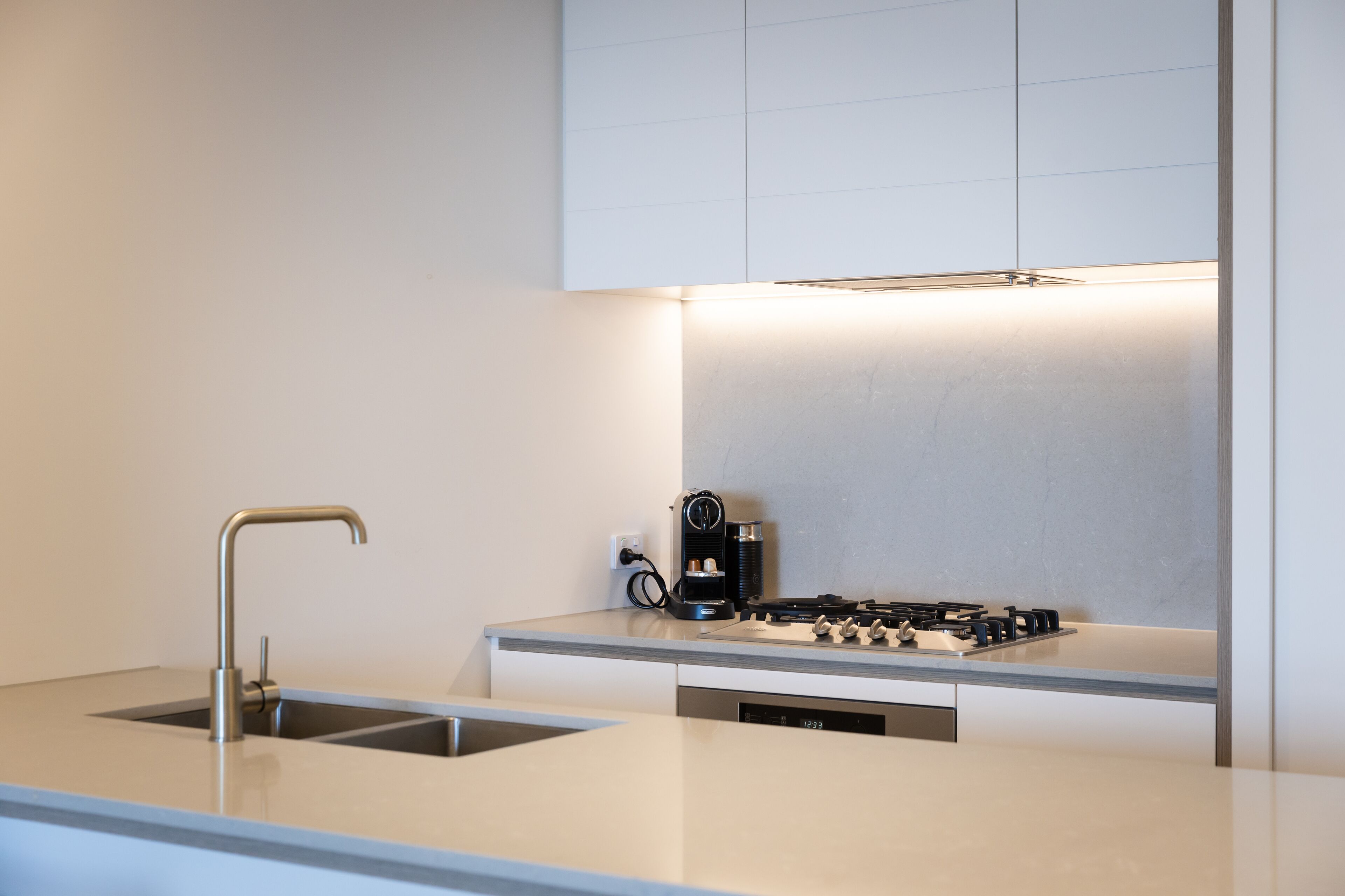 A modern kitchen with a stainless steel sink, a coffee maker, and a dishwasher.