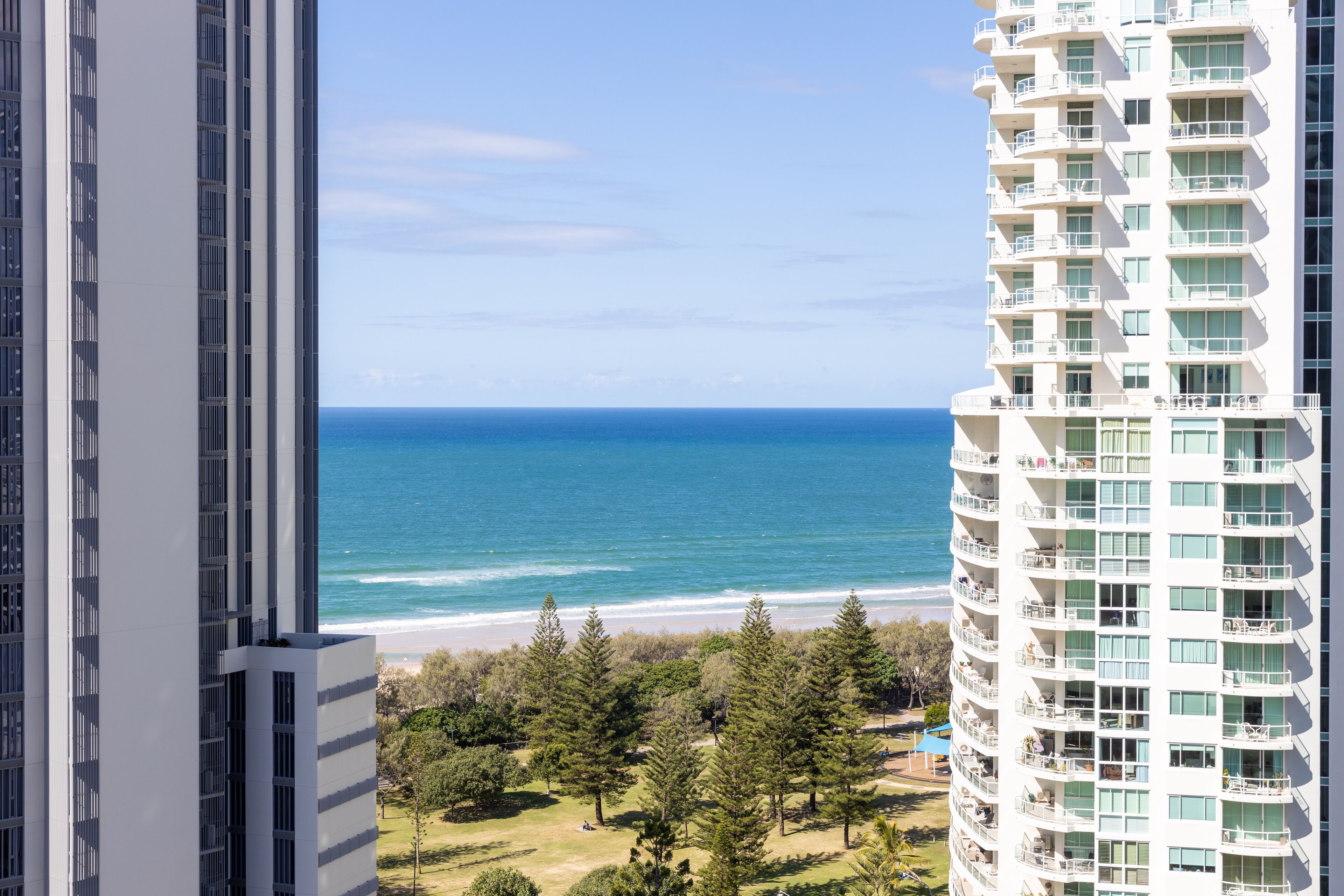 A high-rise hotel with balconies overlooking a beach and ocean.