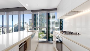 A modern kitchen with a large window, a built-in oven, and a stove. - ULTIQA Signature at Broadbeach (Broadbeach)