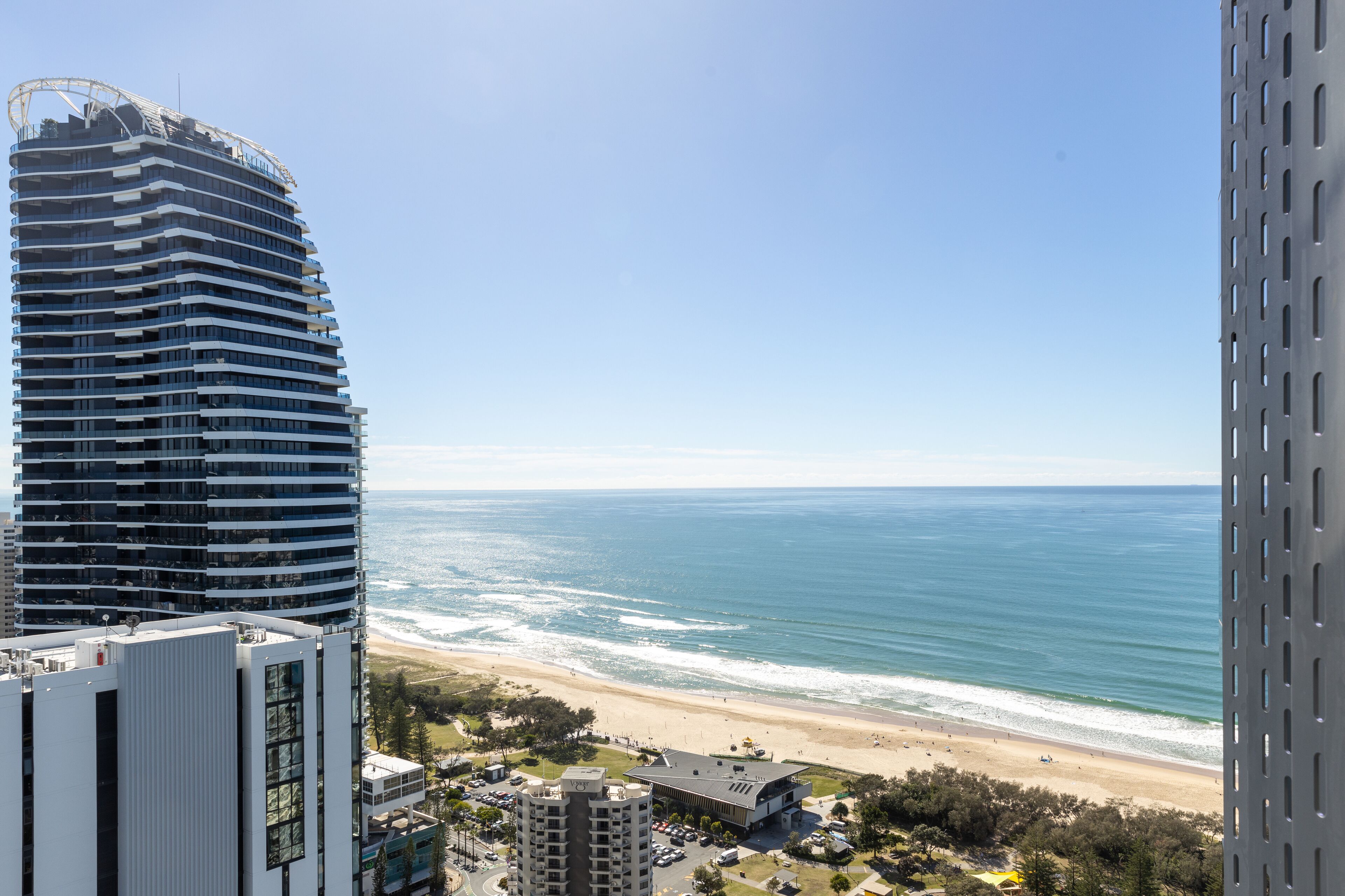 A high-rise building with a curved facade overlooking a beach.