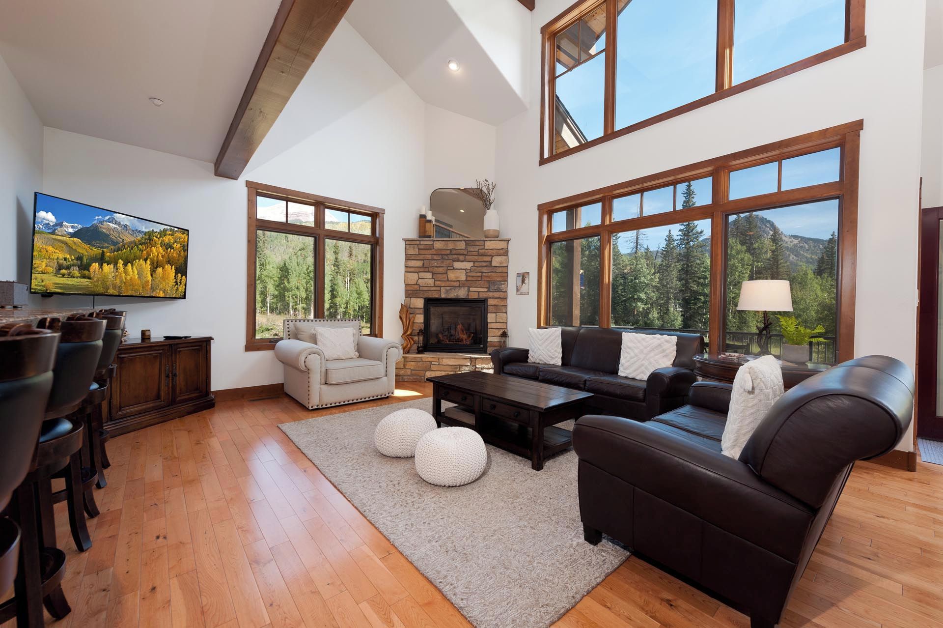 A spacious living room with a fireplace, large windows, and a television.