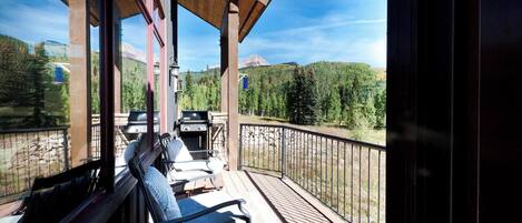A wooden deck with outdoor seating and a view of a mountainous landscape.