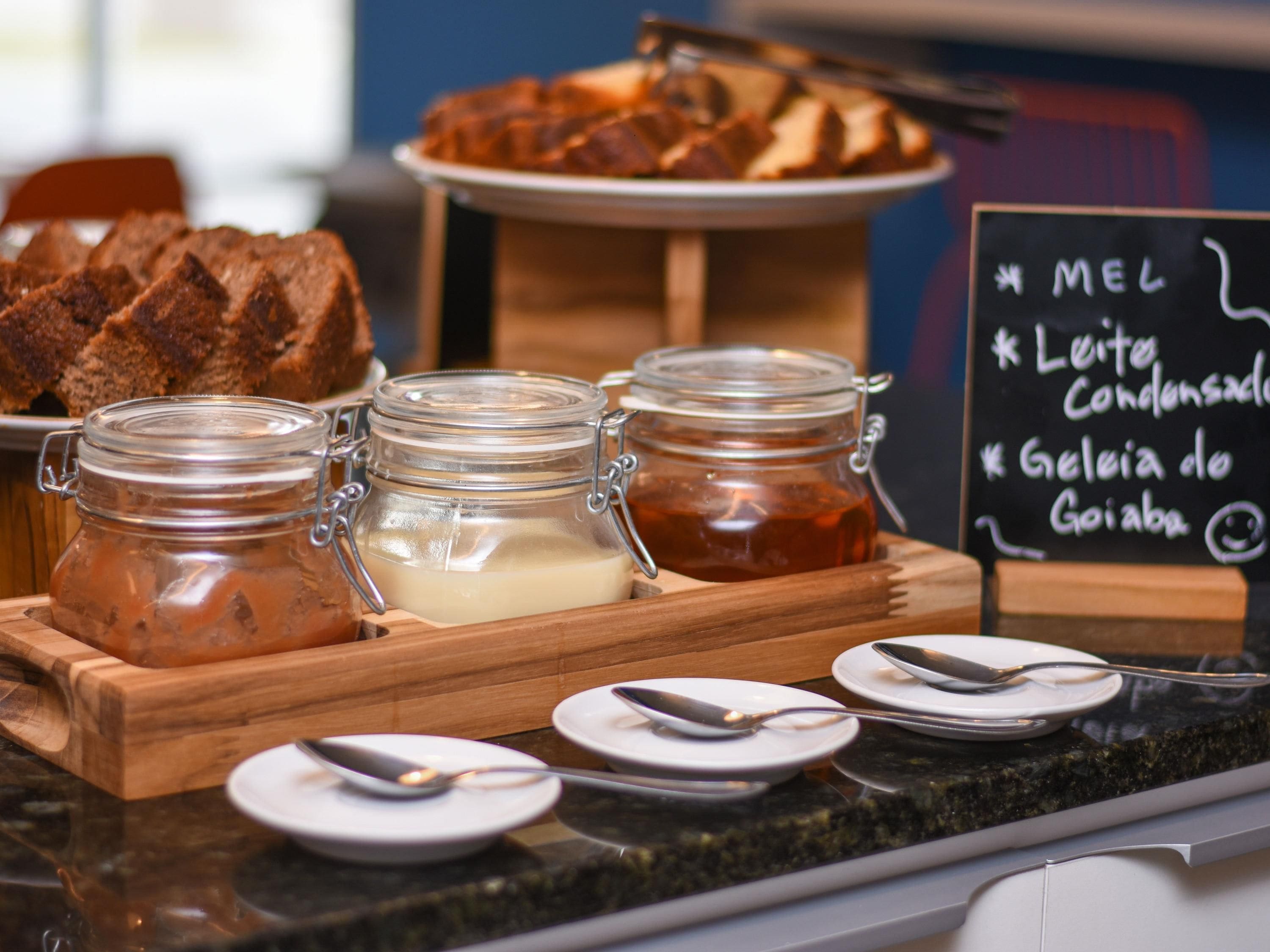 Ein Frühstücksbuffet mit Brot, Marmelade und verschiedenen Aufstrichen.