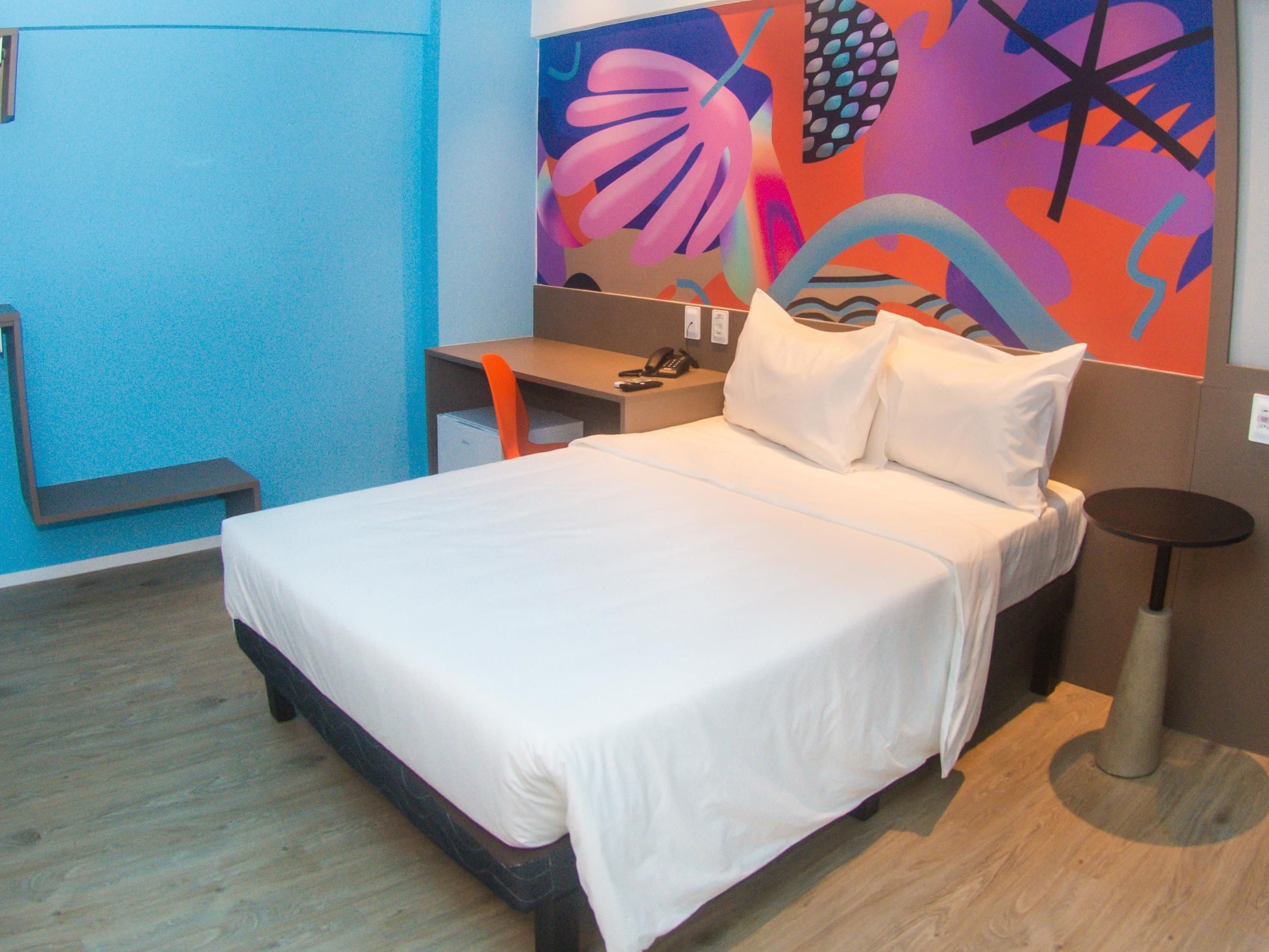 A hotel room with a bed, a desk, and a chair.