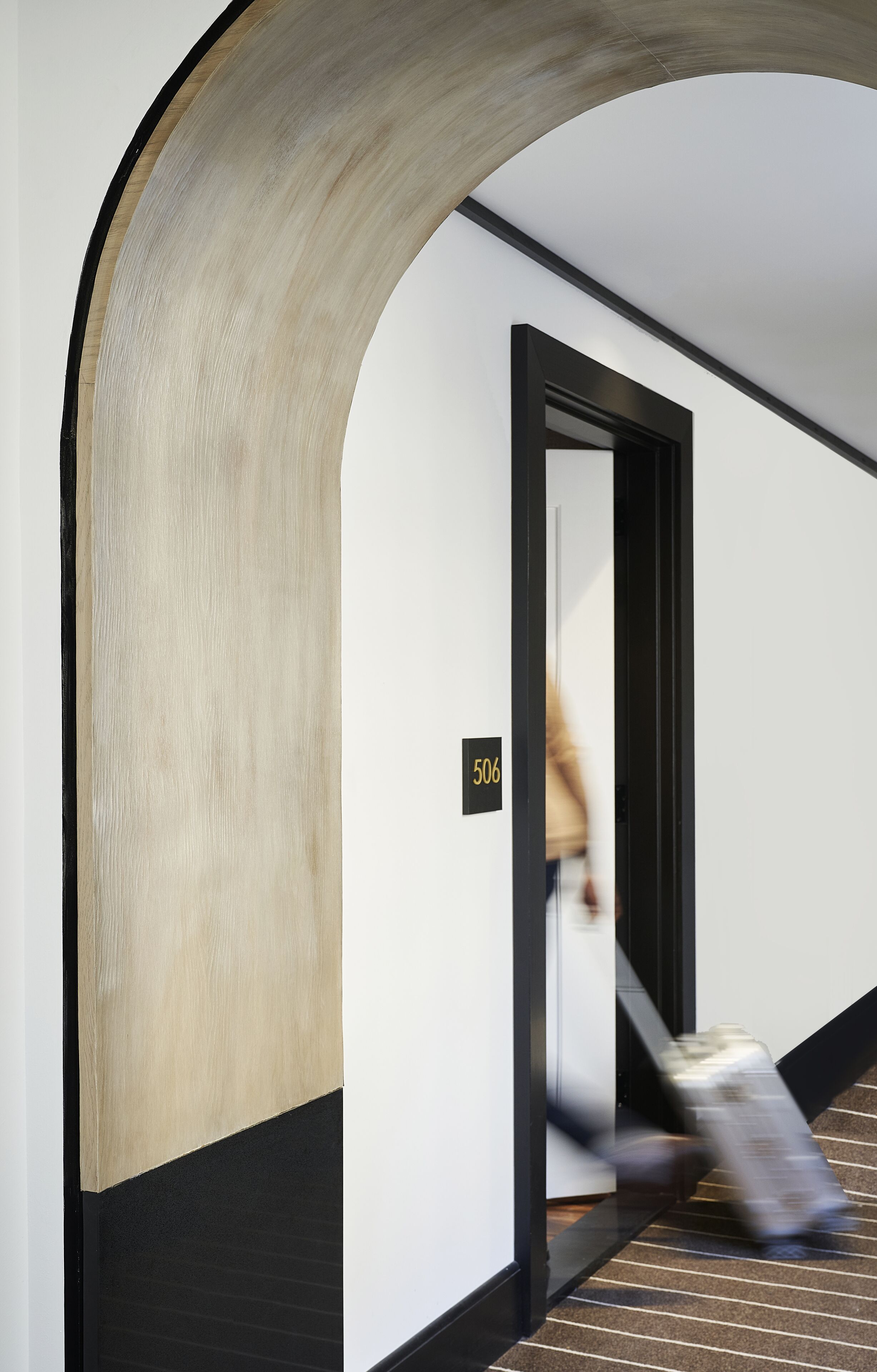 A hallway with a curved wall, a door labeled "506", and a striped carpet.