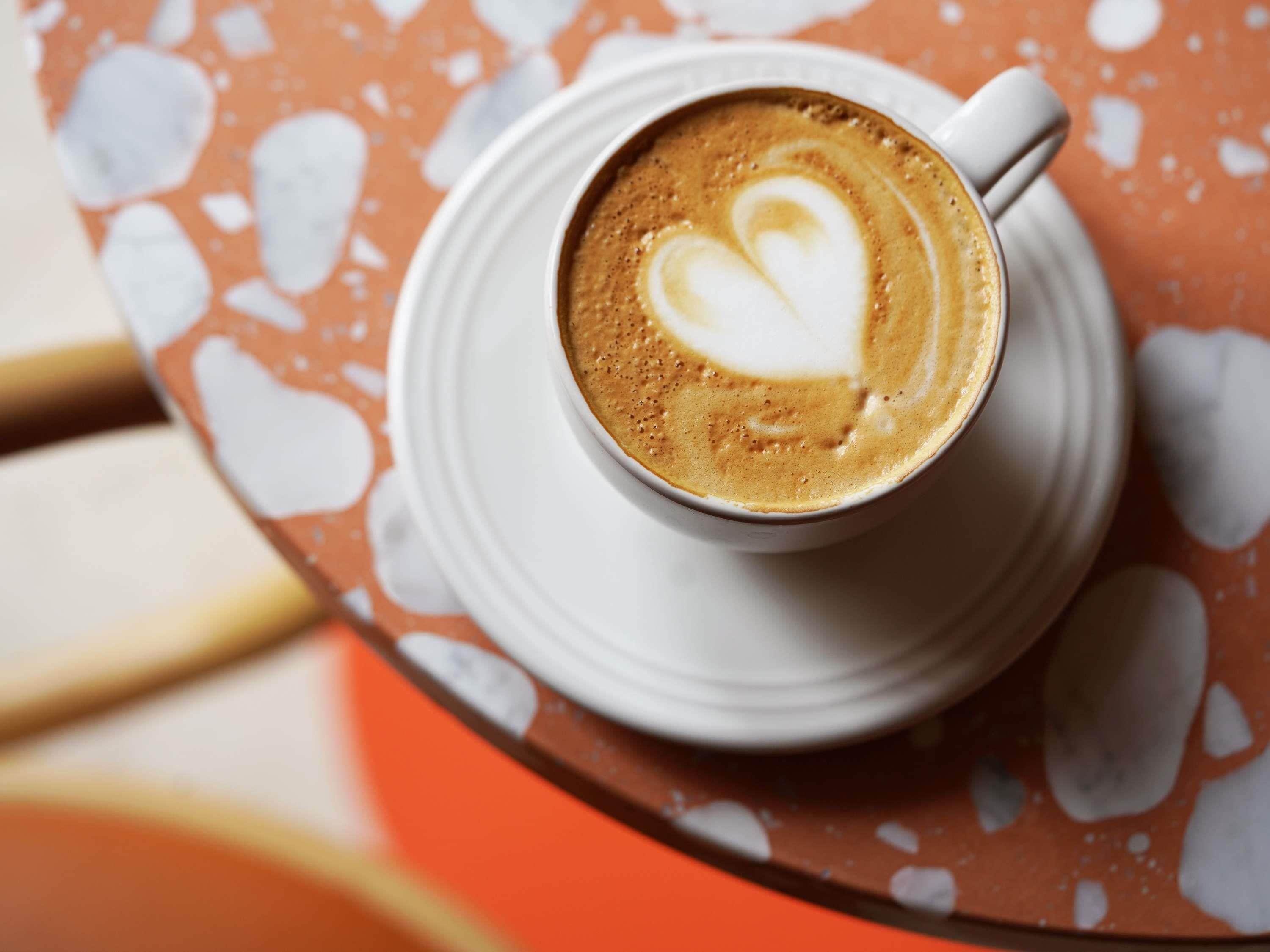 A cup of coffee with latte art on a saucer.