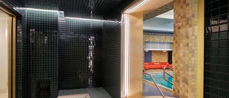 A spa area with a tiled floor, a glass enclosure, and a pool visible through the glass.