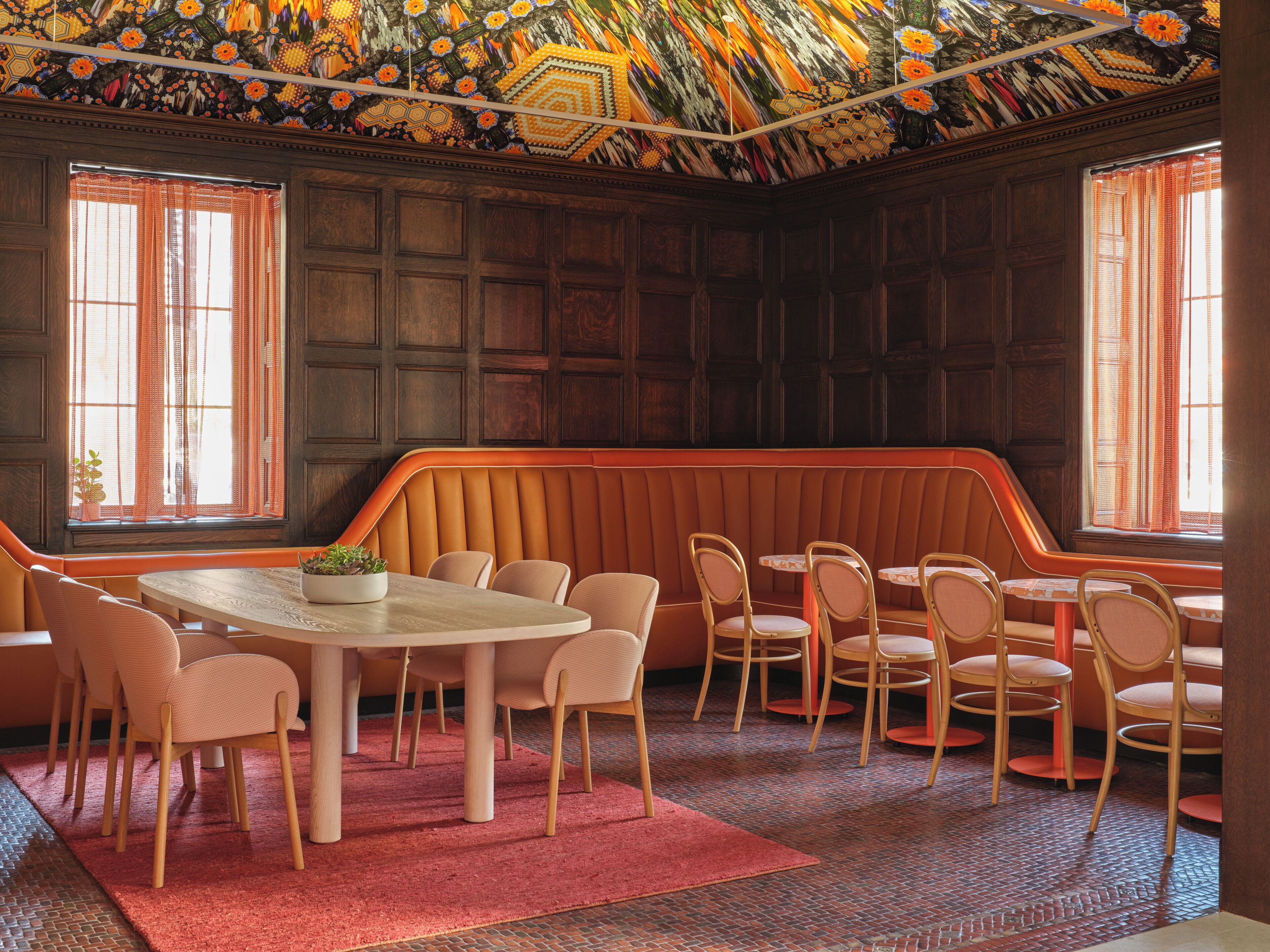 A restaurant with a booth seating area, wooden panel walls, and a patterned ceiling.