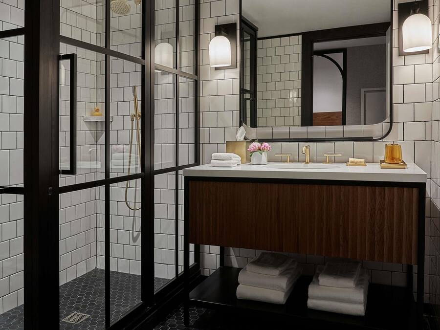 A modern bathroom with a glass-enclosed shower, a wooden vanity, and a large mirror.
