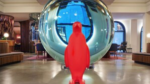 A spacious lobby with a large spherical sculpture, a seating area, and a view of the outside through a large window. - 21C Museum Hotel St Louis  (St. Louis)