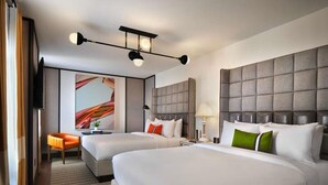 A hotel room with two beds, a sofa, a television, and a painting on the wall. - 21C Museum Hotel St Louis  (St. Louis)