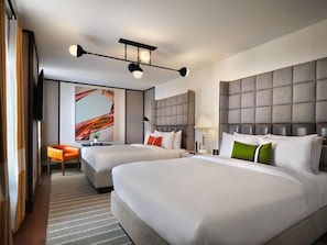 A hotel room with two beds, a sofa, a television, and a painting on the wall. - 21C Museum Hotel St Louis (St. Louis)