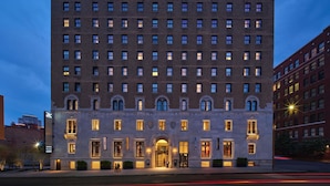 A multi-story building with a symmetrical facade, large windows, and a central entrance with a canopy.