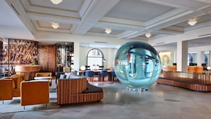 A modern lobby with a large glass sphere, seating areas, and a reception desk.