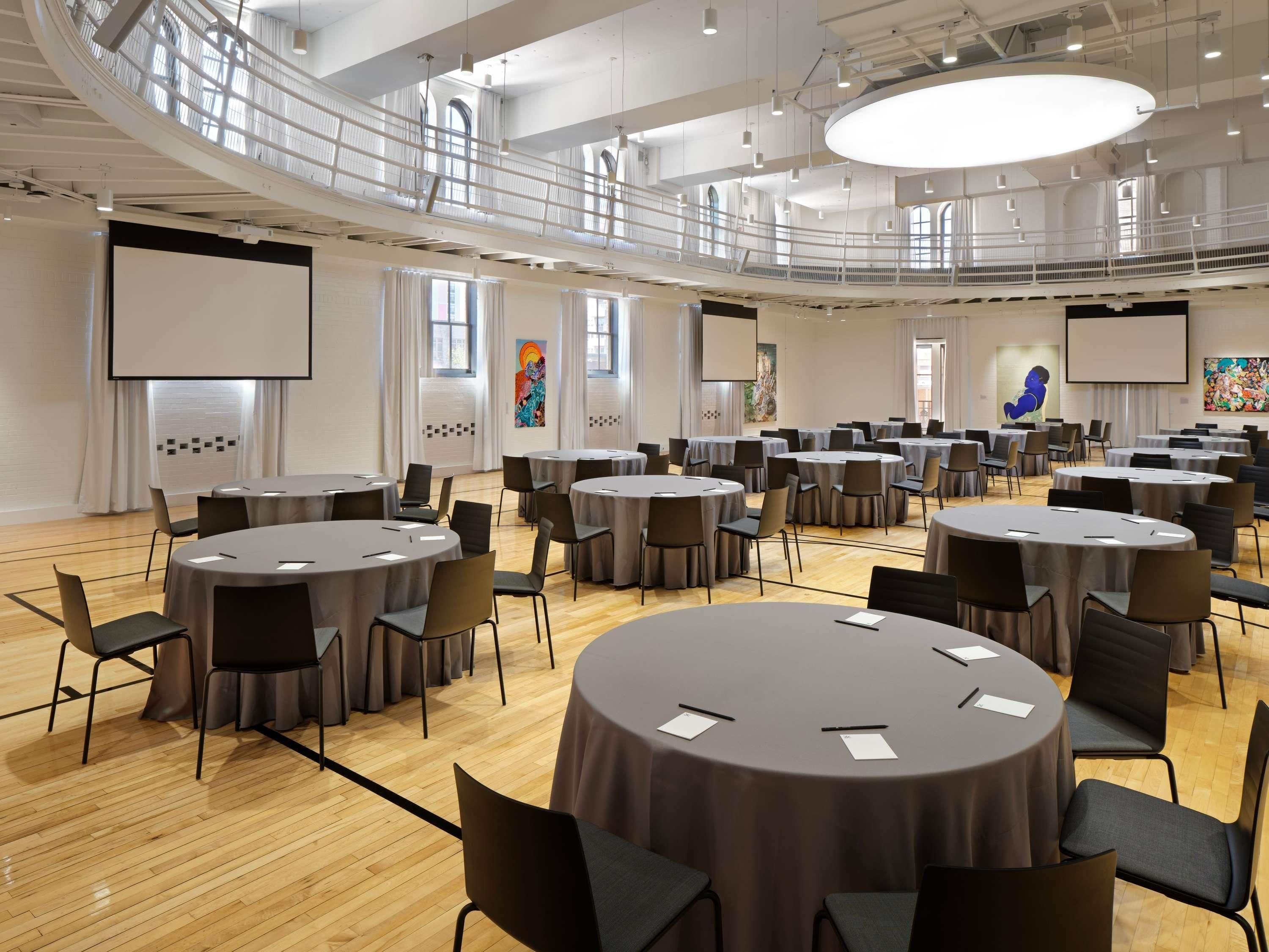 A conference room with multiple round tables, chairs, and a balcony.
