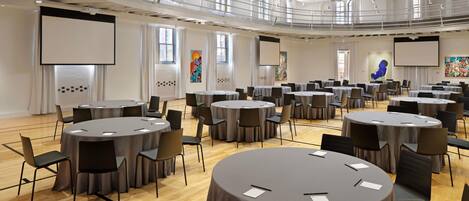 A conference room with multiple round tables, chairs, and a balcony.