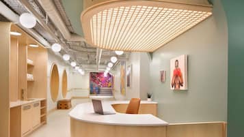 A reception area with a wooden counter, a staircase with a colorful mural, and a sign reading 'Locust Street Athletic and Swim Club.'