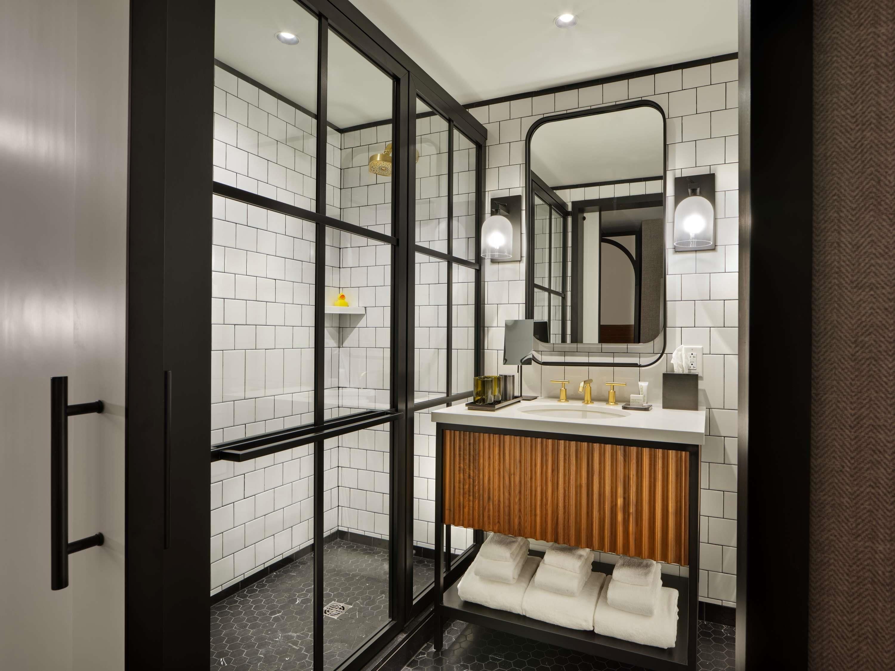 A modern bathroom with a glass-enclosed shower, a wooden vanity, and a large mirror.