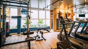Un gimnasio con equipo de ejercicio, amplias ventanas y suelo de madera.