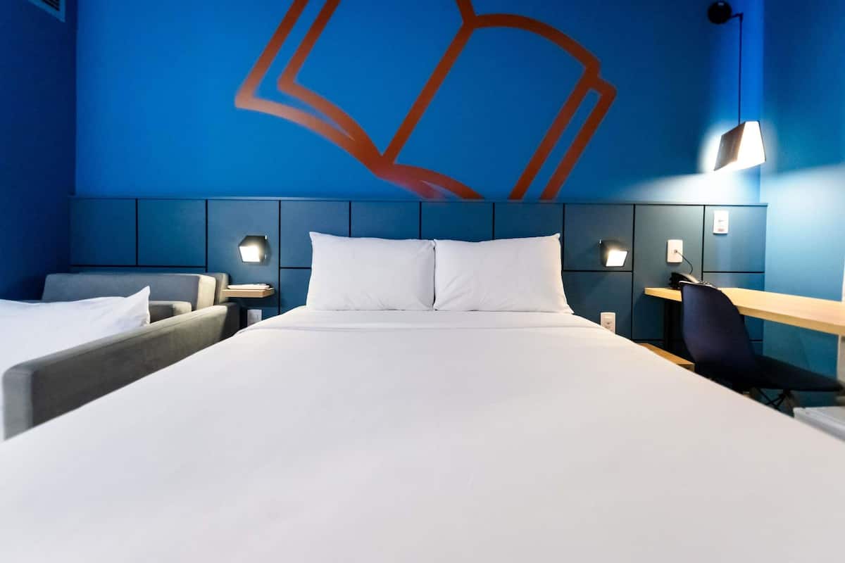 A hotel room with a large bed, two bedside tables, a desk, and a chair.
