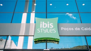 Un escaparate con un letrero verde que dice "ibis Styles" y una vitrina con libros en el interior.