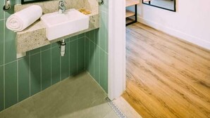Un baño moderno con lavamanos, espejo y barras de apoyo.