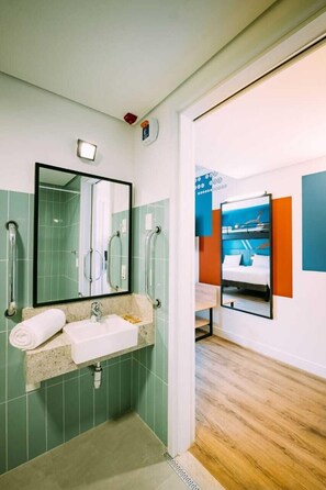 Un baño moderno con lavamanos, espejo y barras de apoyo.