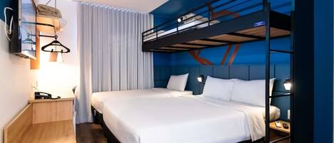 Une chambre d’hôtel avec un lit superposé, un bureau avec un téléphone et un téléviseur fixé au mur.