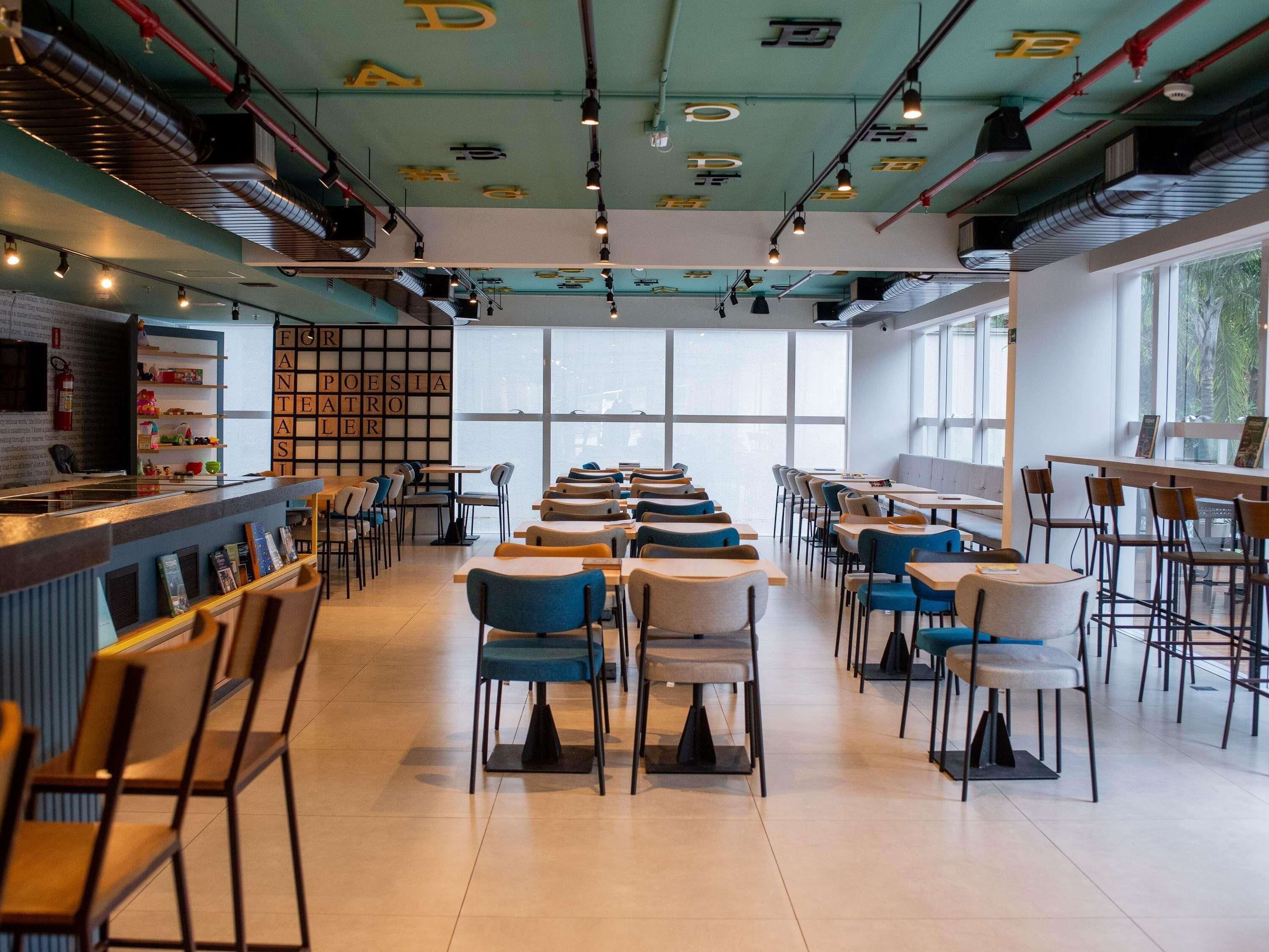 Un café moderne doté d’un bar, de plusieurs espaces pour s’asseoir et de grandes fenêtres qui laissent entrer la lumière naturelle.