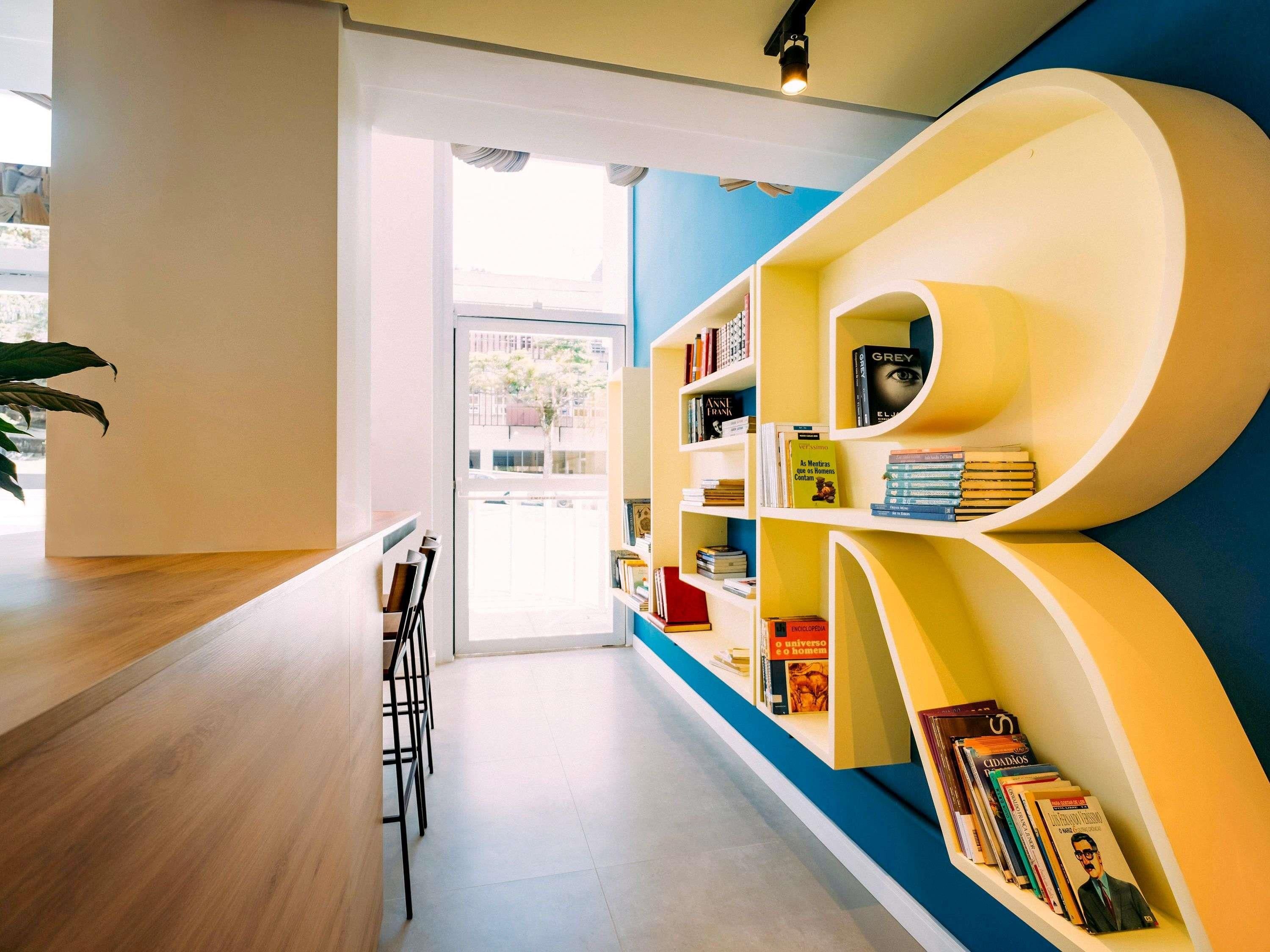 A modern library with bookshelves, a wooden table, and chairs.