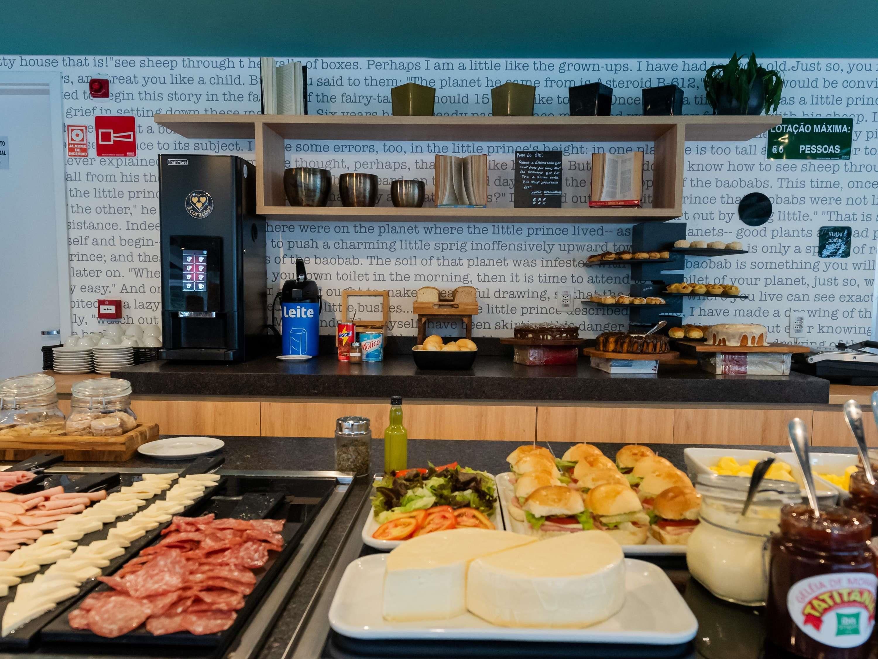 A buffet with various food items, a coffee machine, and a wall with text and decorative items.