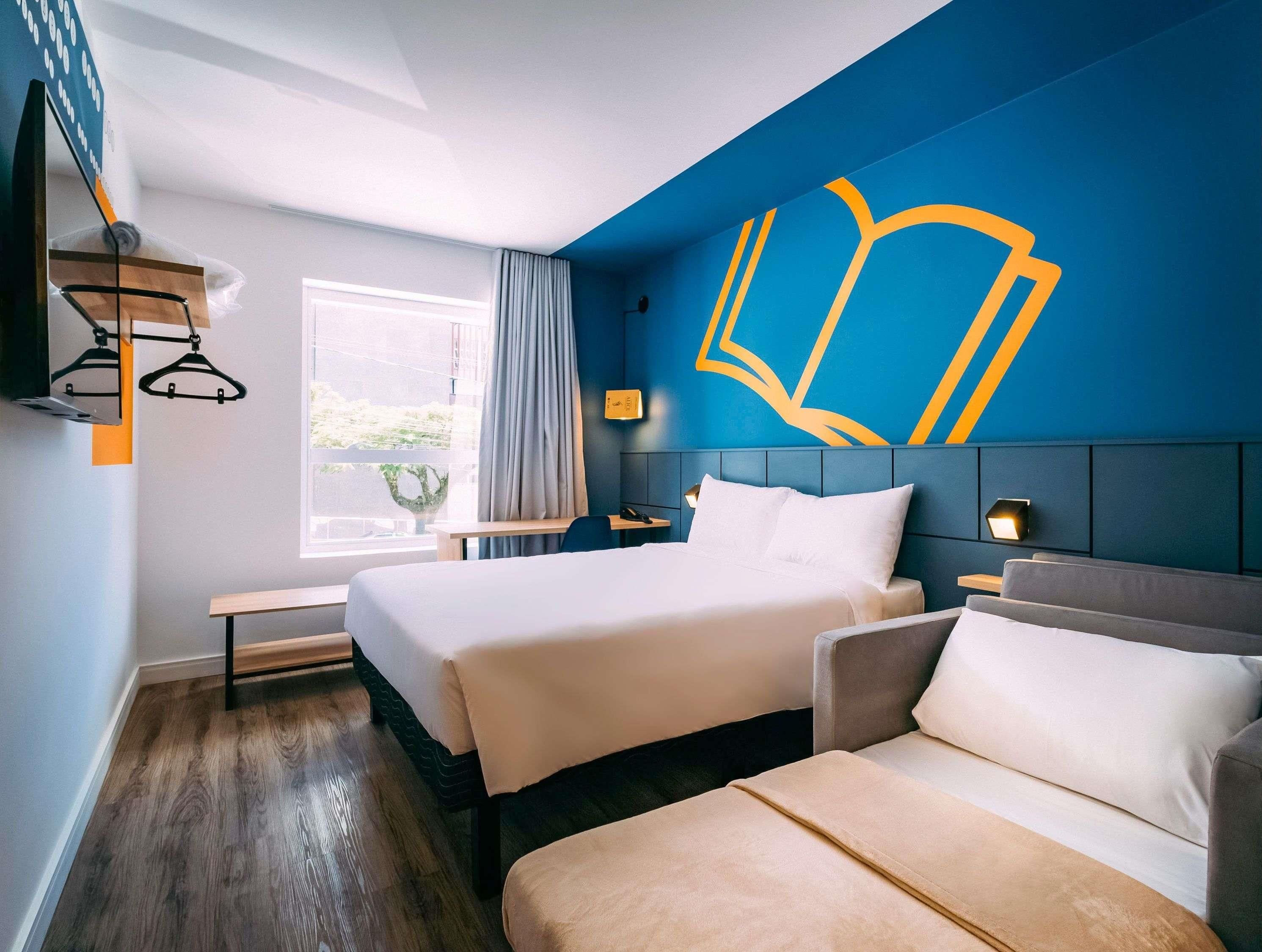 Ett hotellrum med en stor säng, en soffa, ett skrivbord och ett fönster med gardiner.
