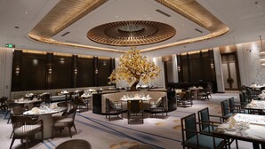 A modern hotel lobby with a central seating area, multiple dining tables, and a distinctive ceiling design. - Sofitel Xiong An (Baoding)