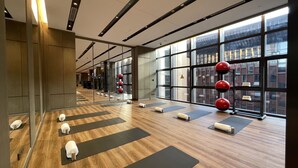 A modern gym with wooden floors, black yoga mats, and red exercise balls. - Sofitel Xiong An (Baoding)