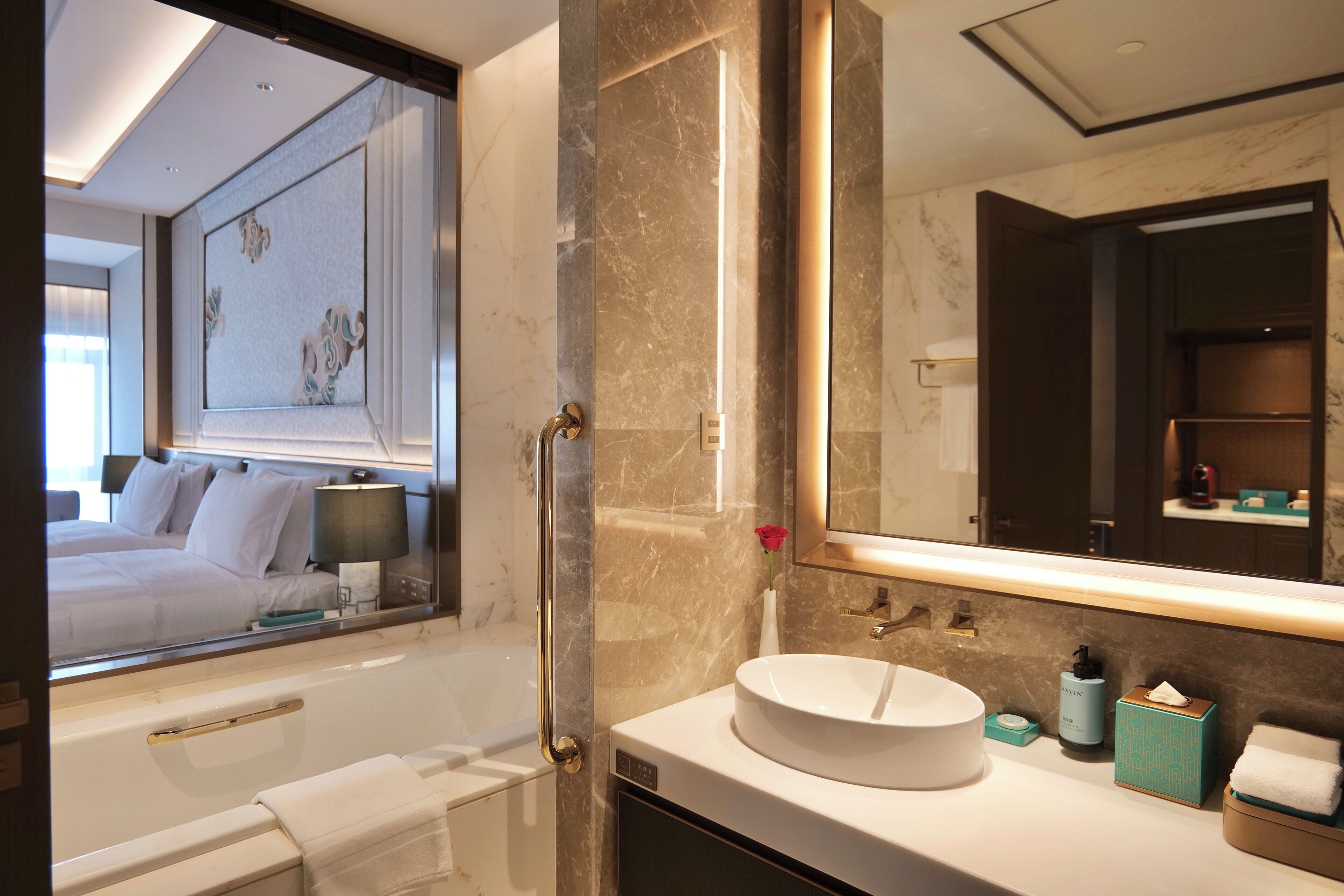 A modern bathroom with a large mirror, a round sink, and a bathtub.