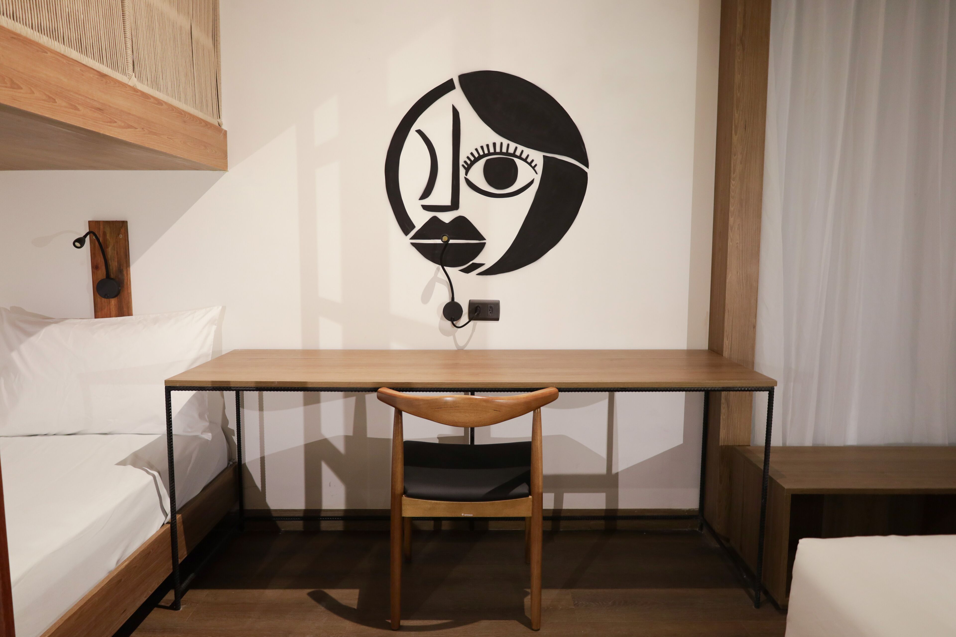 A minimalist room with a wooden desk, a chair, and a bed.