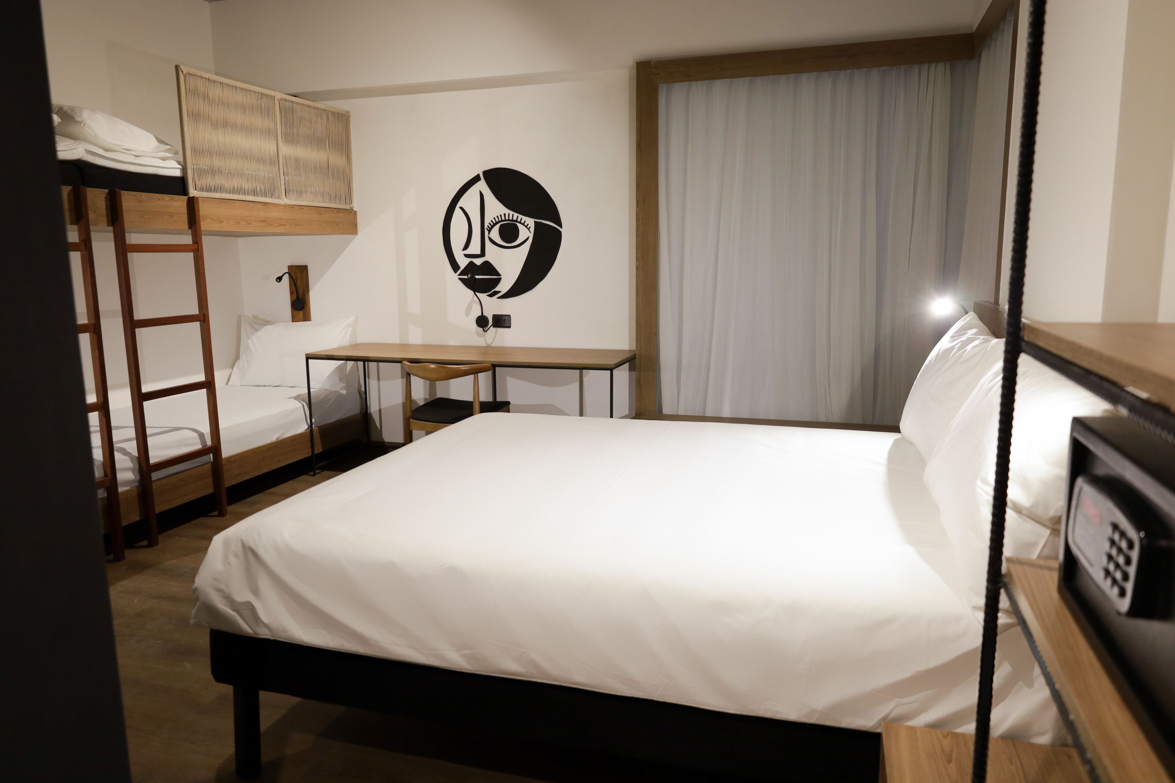 A hotel room with a bunk bed, a desk, and a wall-mounted artwork.