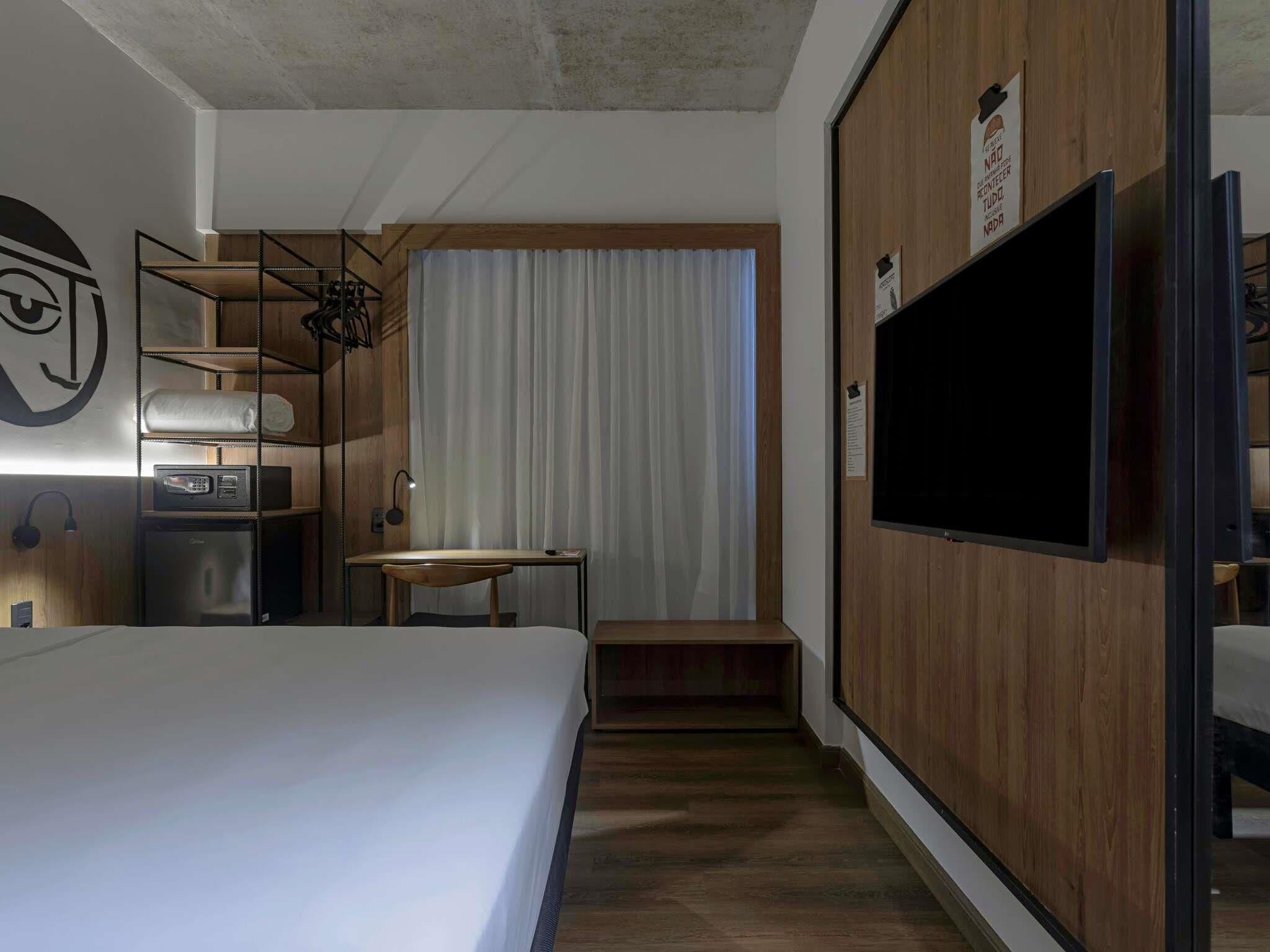 Une chambre d’hôtel équipée d’un lit, d’un bureau, d’une chaise, d’une télévision et d’une armoire.