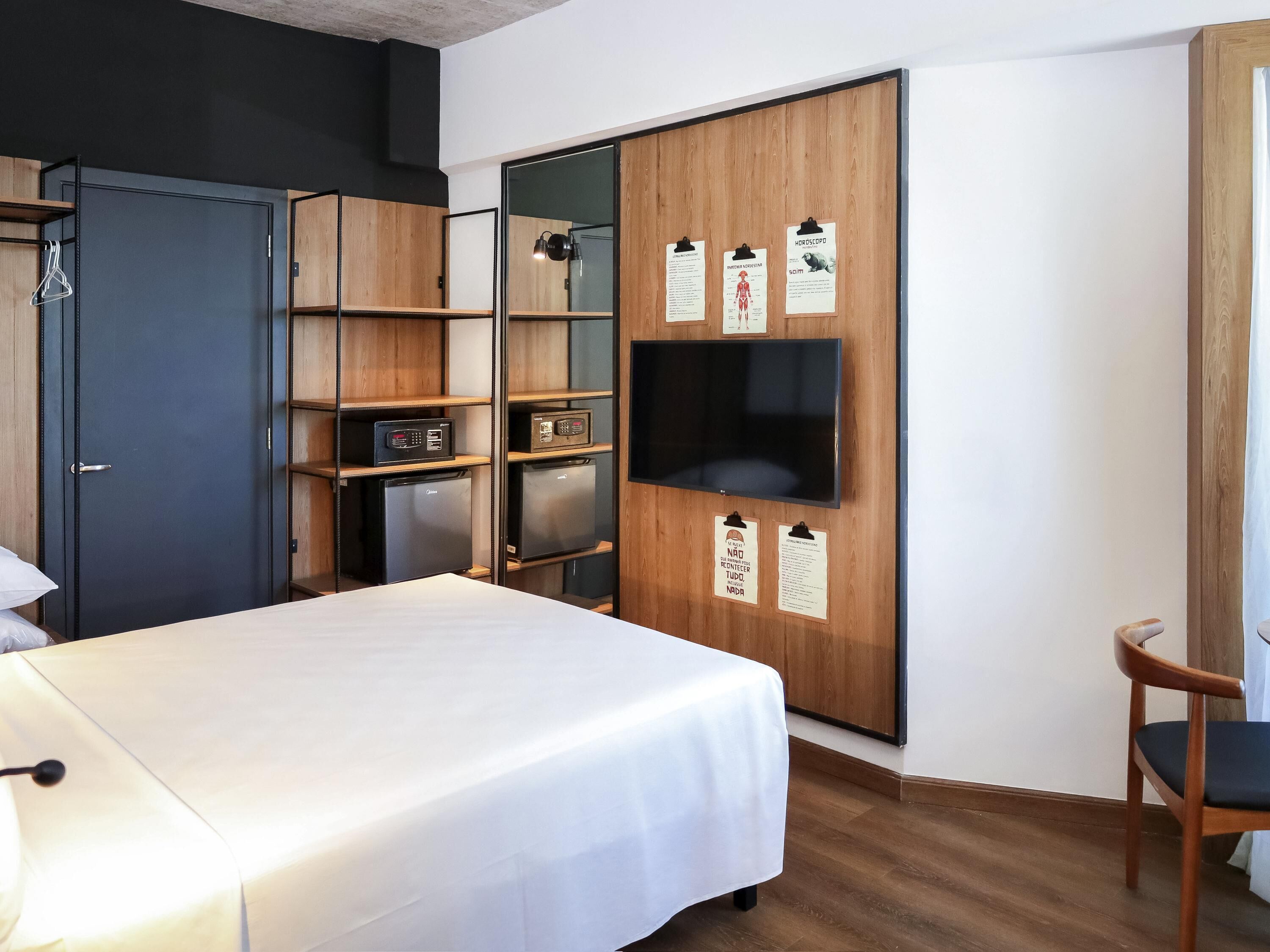 A hotel room with a bed, a desk, a wardrobe, and a television.