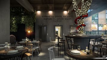 A modern restaurant interior with tables set for dining, a bar area, and a wall with a quote in a foreign language.
