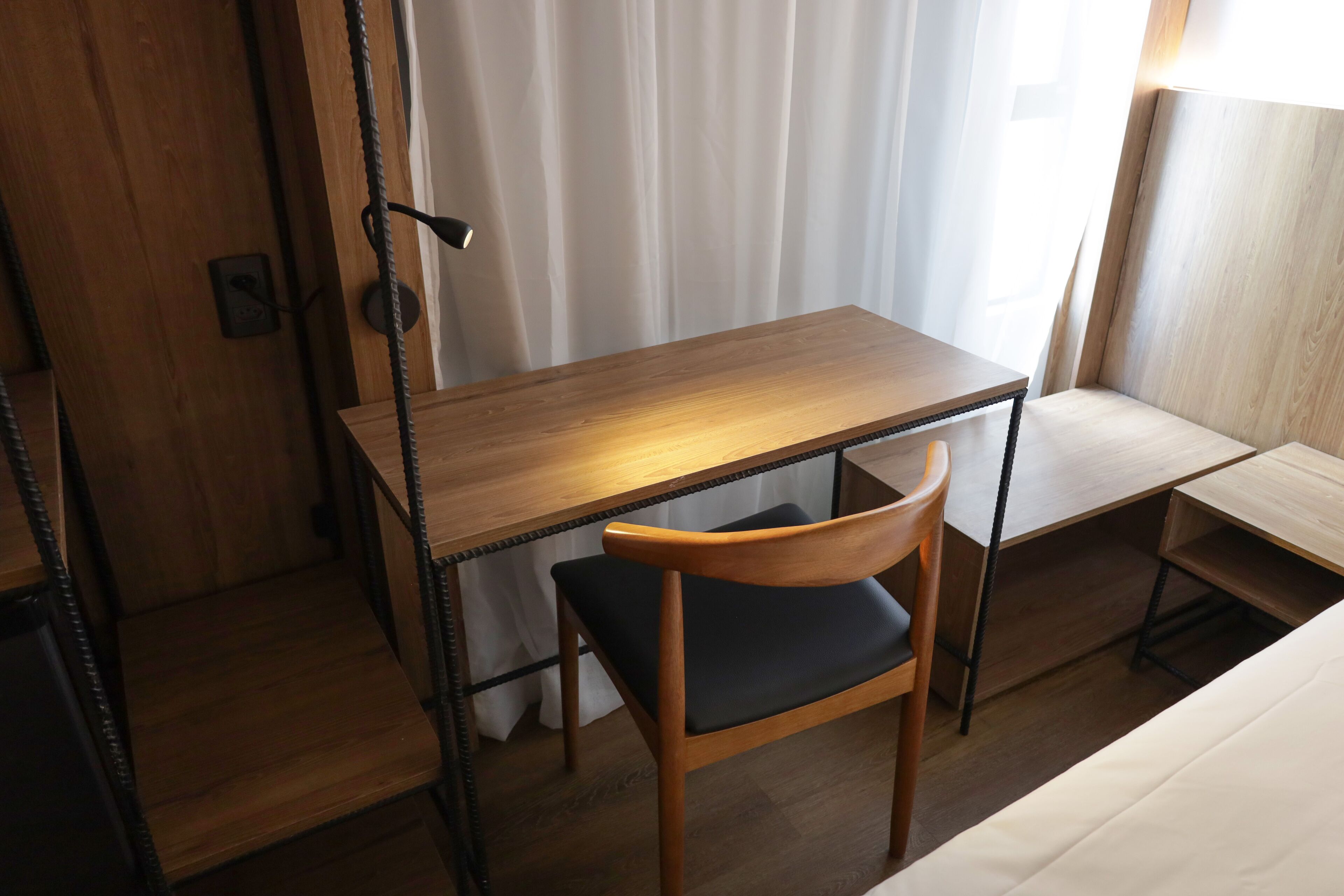 Una habitación pequeña y ordenada con un escritorio de madera, una silla y una cama.
