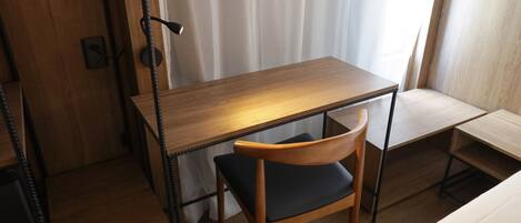 Una habitación pequeña y ordenada con un escritorio de madera, una silla y una cama.