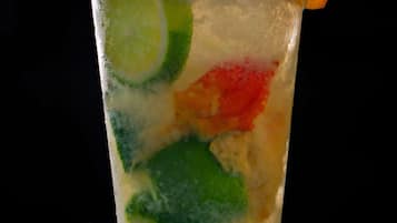 Un vaso con cubitos de hielo y trozos de fruta colorida.