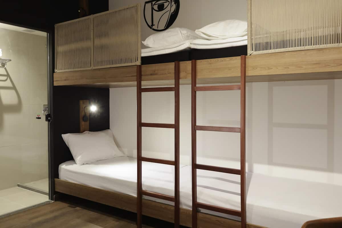 A bunk bed room with a wooden ladder, a headboard, and a wall-mounted shelf.
